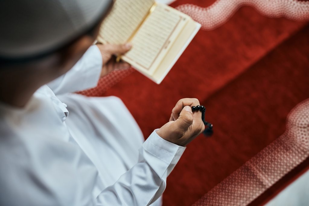 Muslim man holding prayer beads while purifying wealth